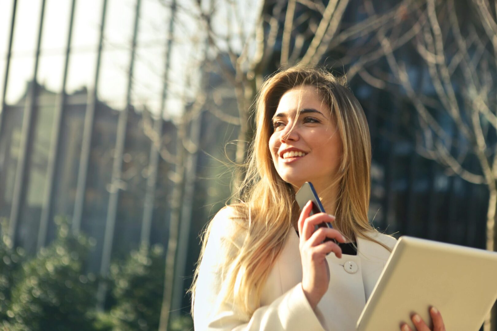 A woman holding a cell phone and looking up at the sky.